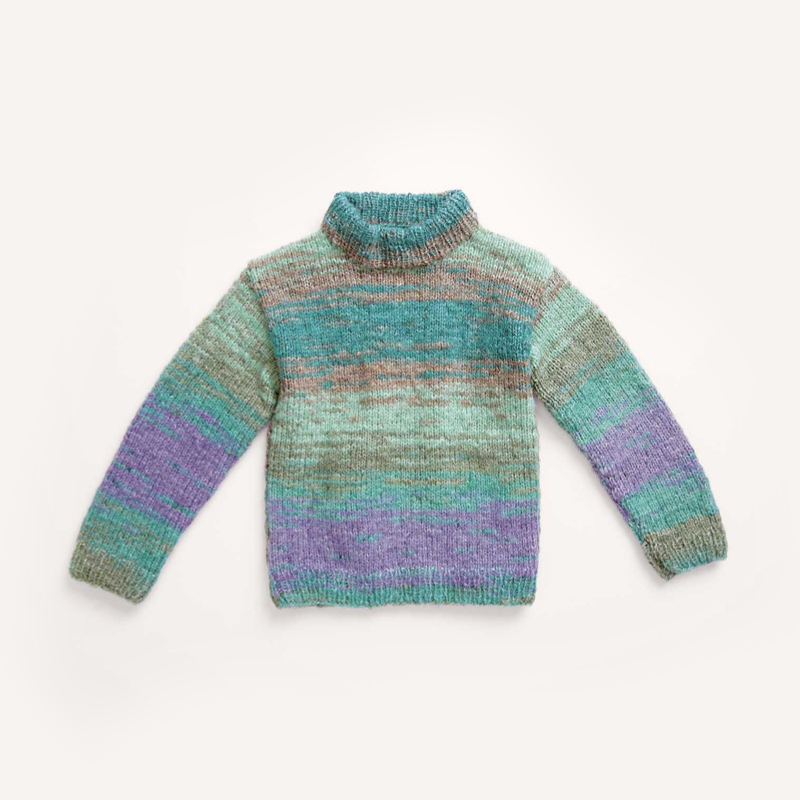 Gestrickter Kinderpullover mit Farbverlauf liegt auf grauem Hintergrund.