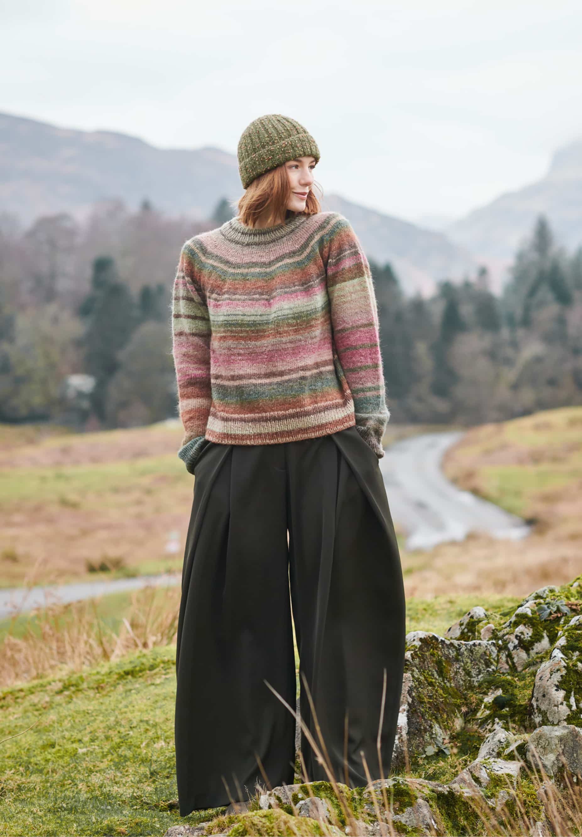 Frau trägt gestrickten Pullover mit Farbverlauf in Grün- und Rottönen: Modell 27 aus Lovewool No. 23