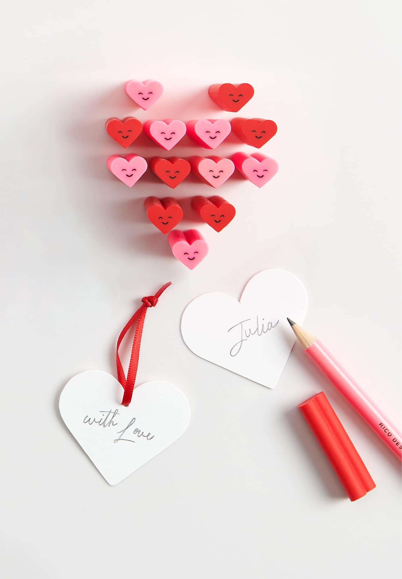 Radiergummis in Herzform sind zu einem Herz aufgestellt. Karten und Stift liegen dabei.