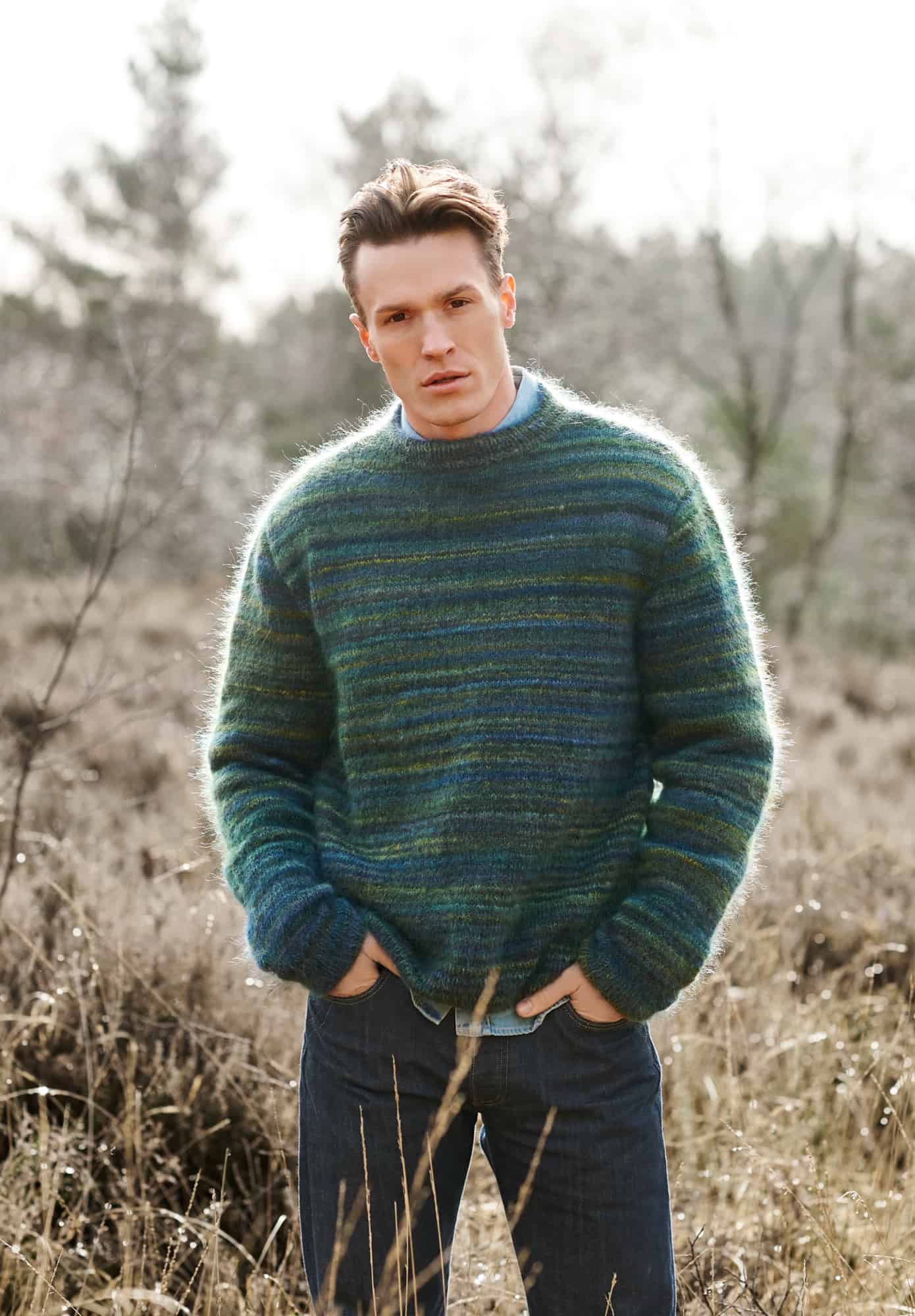Mann trägt gestrickten Pullover mit Farbverlauf in Blau und Grüntönen: Modell 09 aus Lovewool No. 21