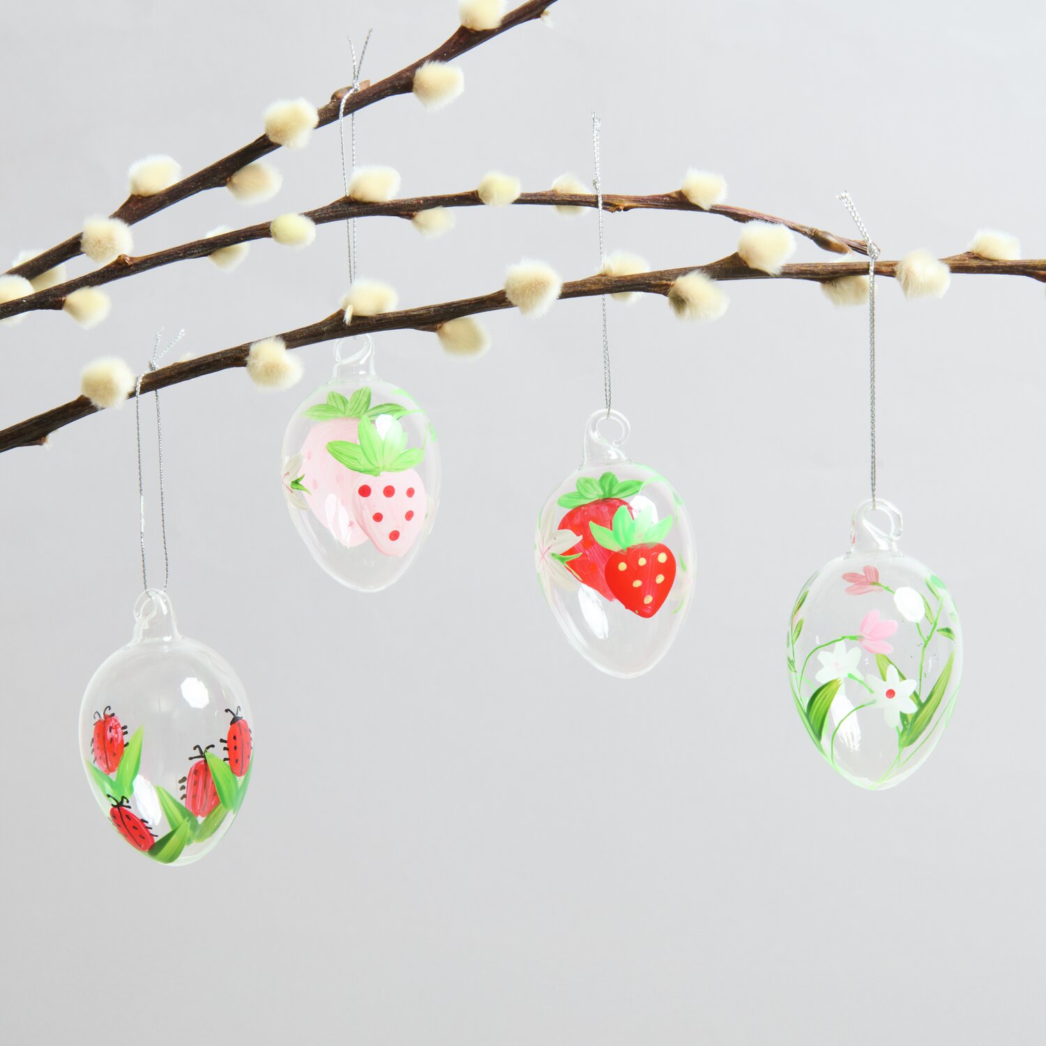 Glas Eier Erdbeeren/Marienkäfer 4 Stück: Transparente Deko-Eier mit Erdbeer- und Marienkäfer-Motiven an einem Ast hängend.