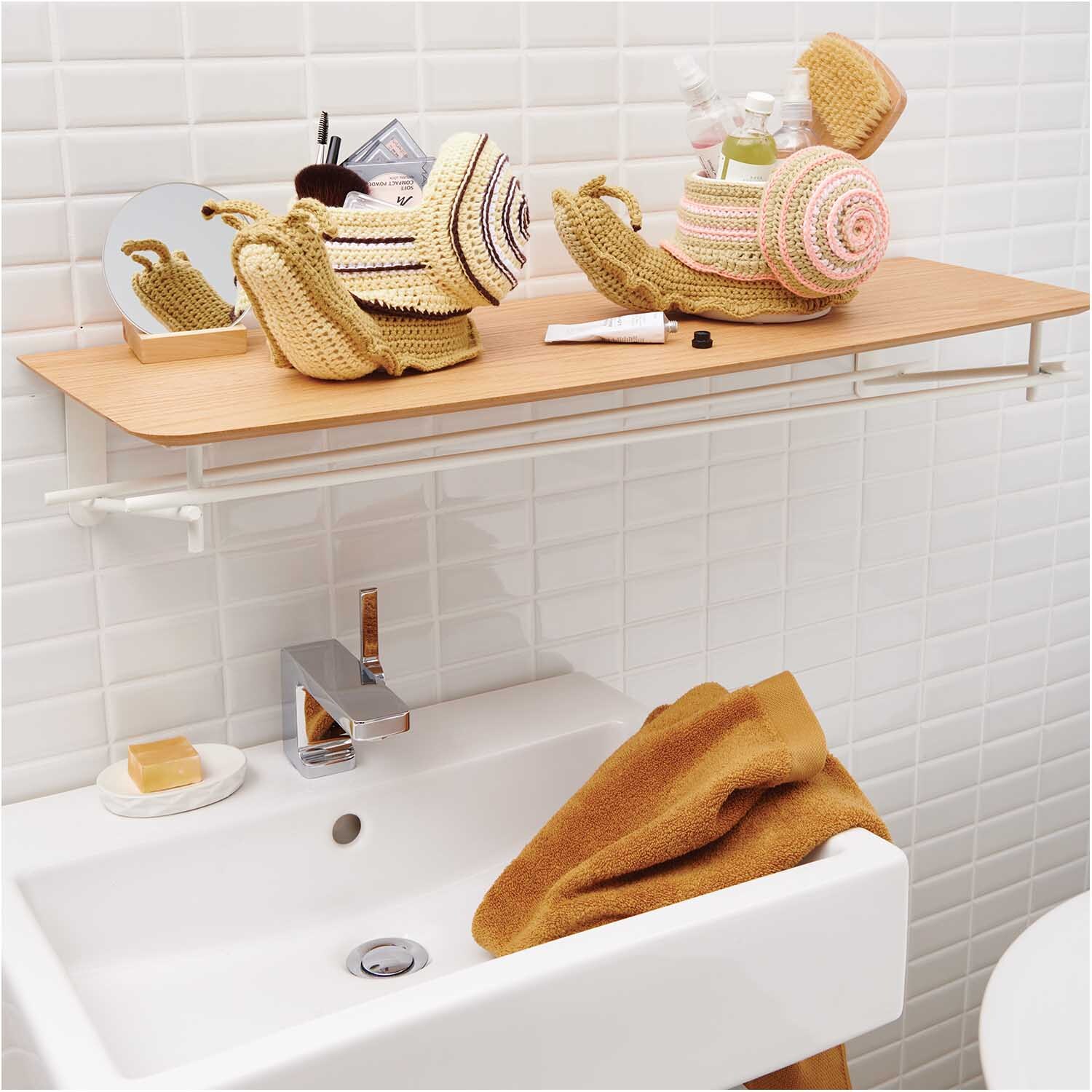 Creative Cotton aran: Zwei gehäkelte Schnecken auf einem Regal über einem Waschbecken, dekorativ platziert.