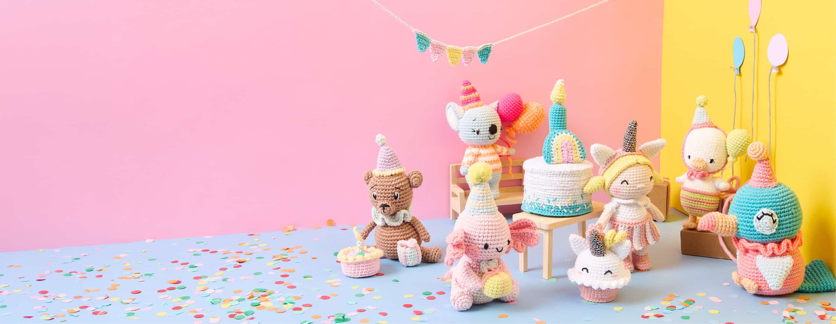Sieben Amigurumis zum Thema Birthday Party sind mit Partyaccessoires vor bunten Wänden dekoriert. 