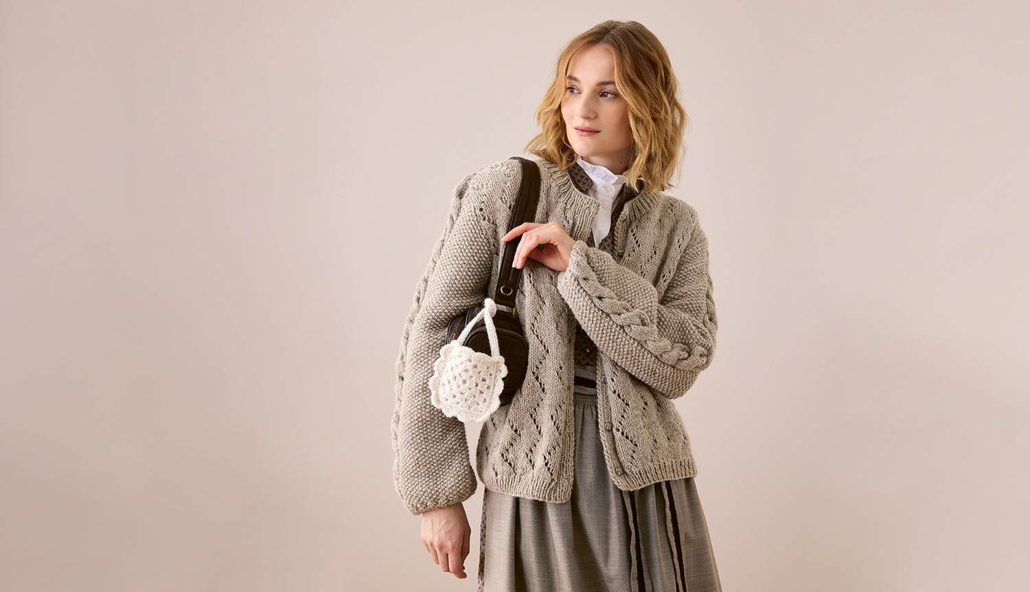 Trachtenjacke aus Soft Alpaca: Elegante, graue Jacke mit Zopfmuster, kombiniert mit einem weißen Hemd und grauem Rock. Ideal für stilvolle Anlässe.