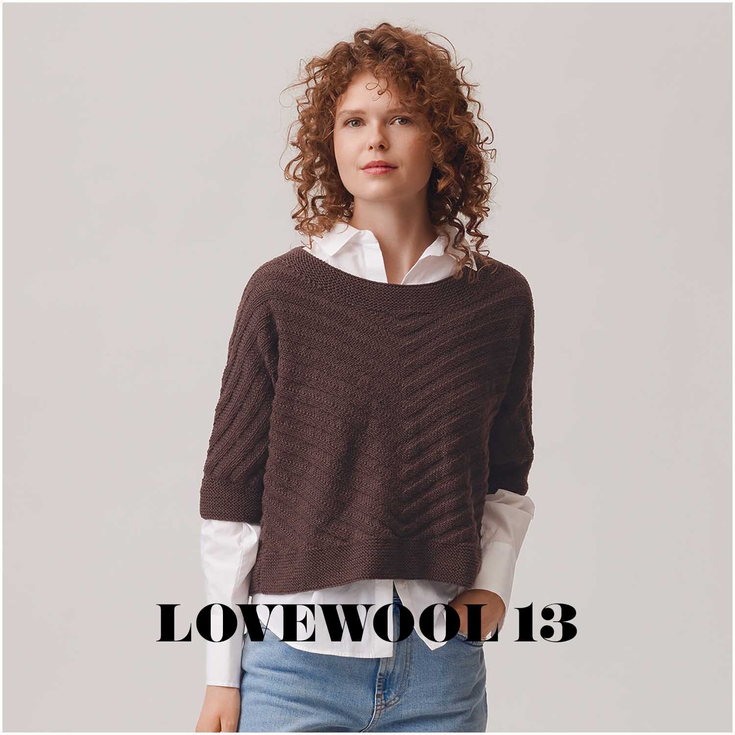 Essentials Merino dk Pullover in Taupe, getragen von einer Frau mit lockigem Haar, über weißer Bluse.