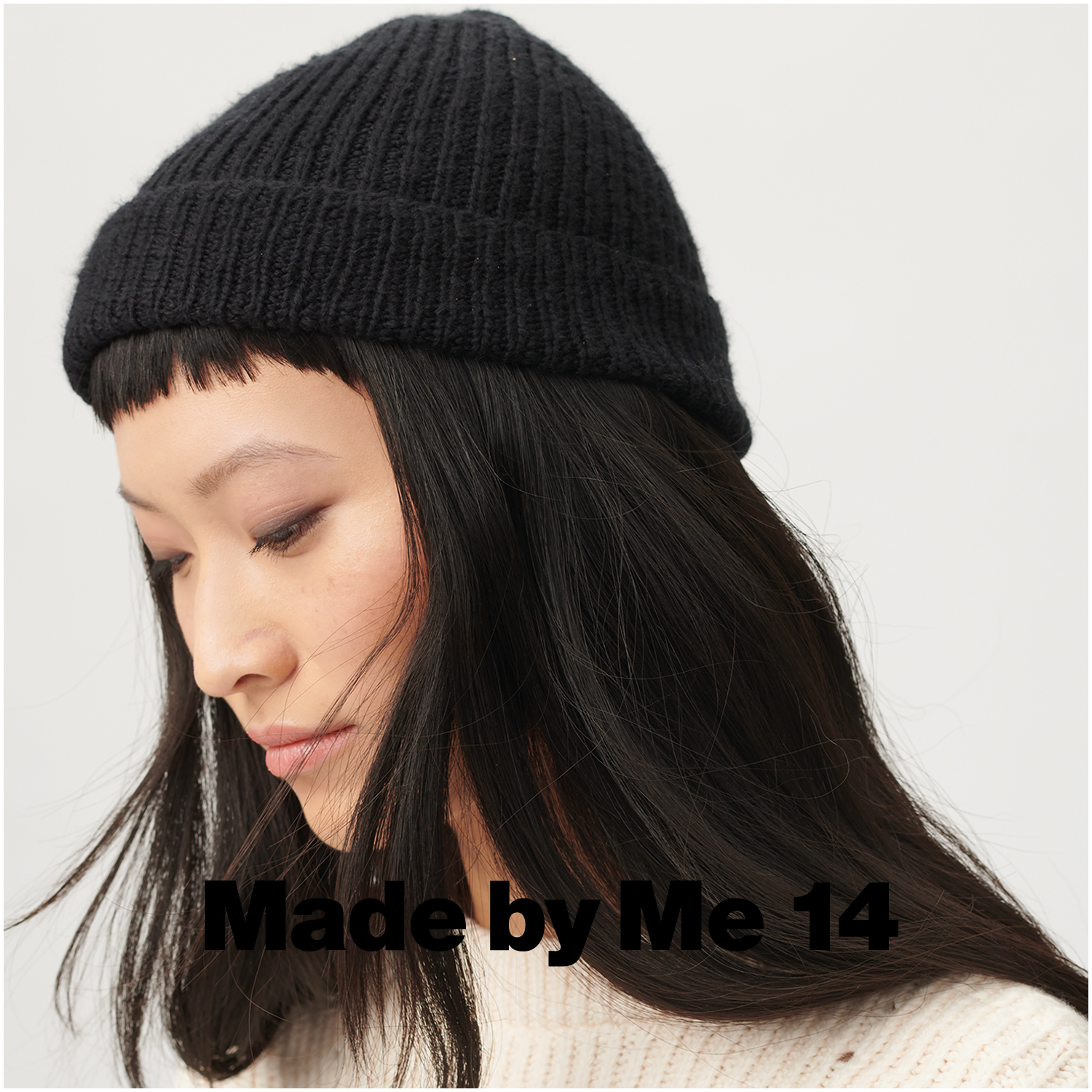 Fashion Cottony: Frau trägt schwarze Strickmütze von Rico Design, kombiniert mit cremefarbenem Pullover.