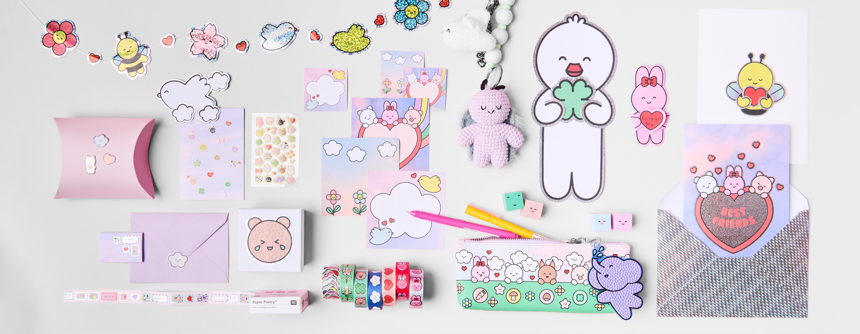 Diverse Papeterie-, Dekoartikel und Häkelfiguren mit liebevoll illustrierten Tierfiguren liegen angeordnet auf grauem Hintergrund. 