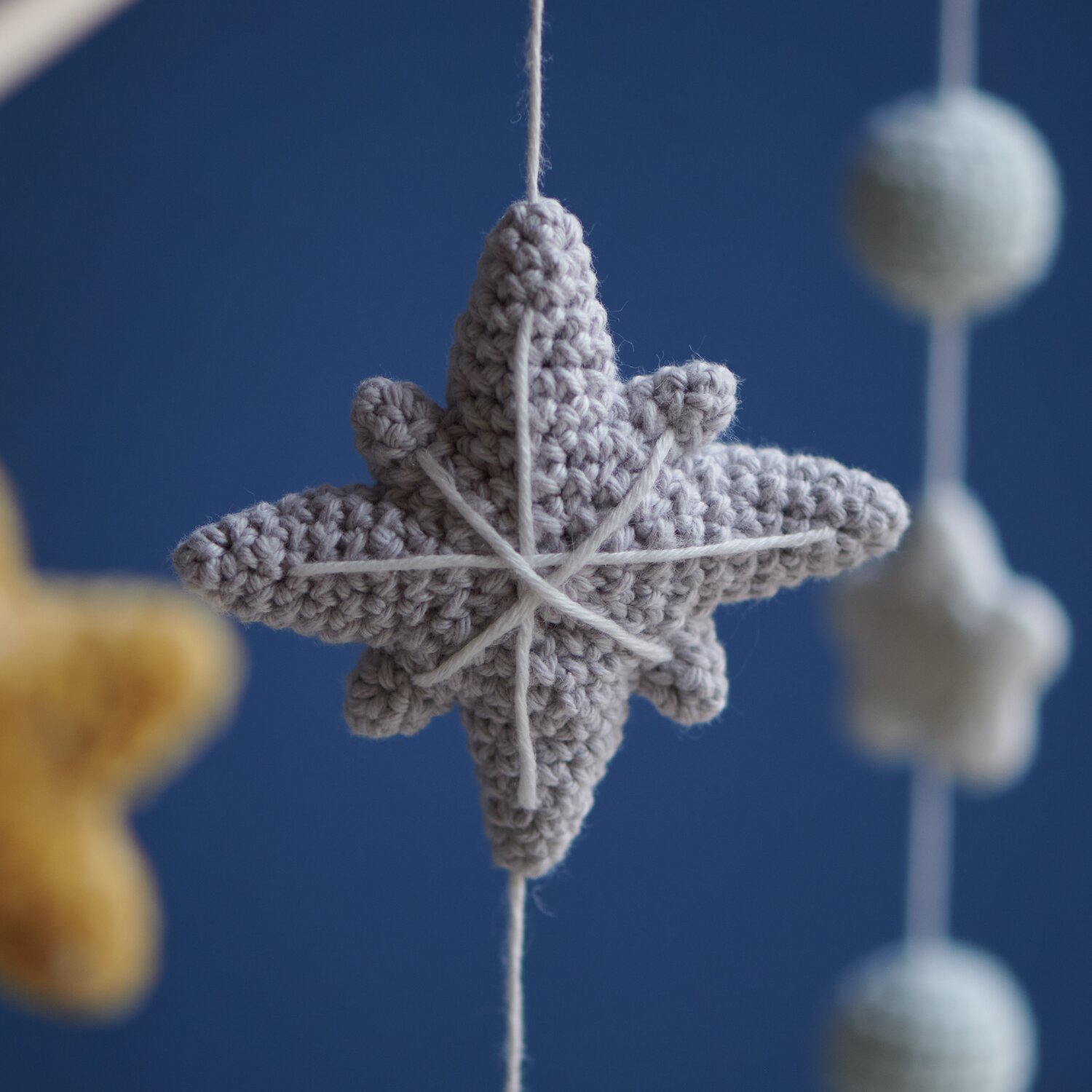 Ricorumi Glow In The Dark: Gehäkelter silbergrauer Stern aus Creative Ricorumi dk vor blauem Hintergrund.