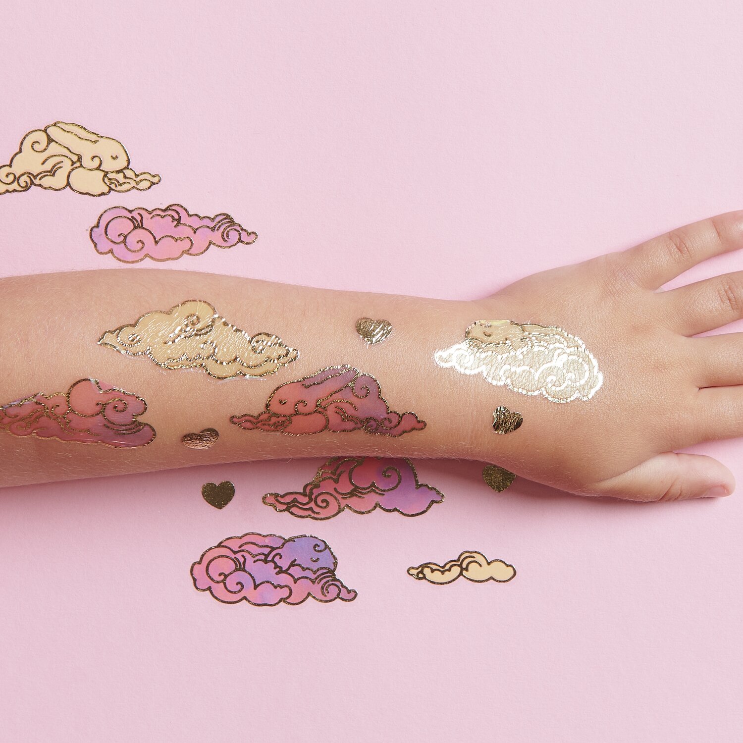 Tattoos Wolken: Temporäre Wolken-Tattoos in Rosa und Gold auf einem Arm, 24-teilig.