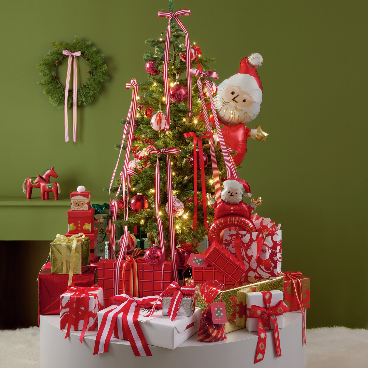 Papierschachtel-Set von Rico Design in Rot, bestehend aus 4 Stück, präsentiert vor einem festlich geschmückten Weihnachtsbaum mit Geschenken und Dekorationen. Perfekt für kreative Geschenkverpackungen.