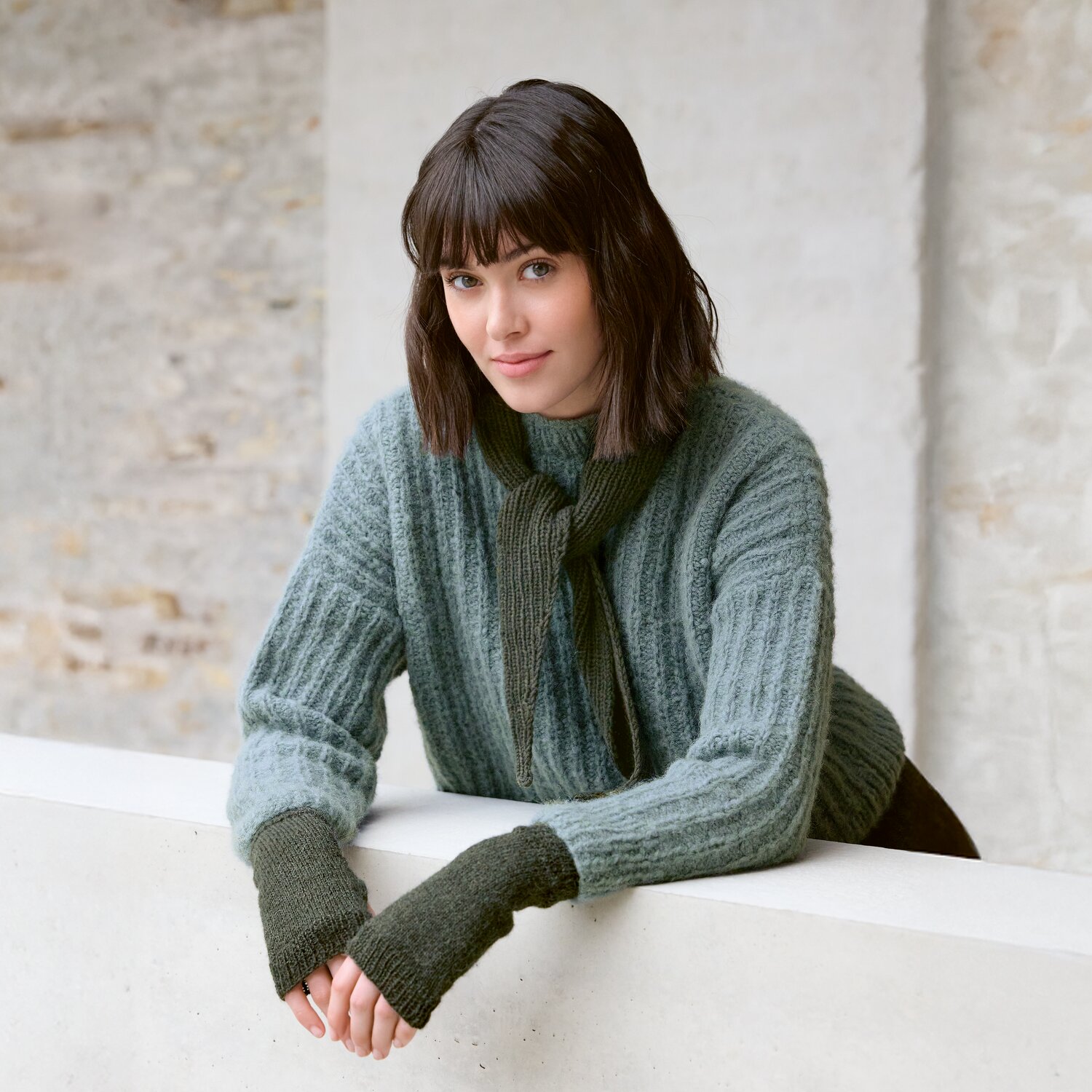Strickset Mini-Dreieckstuch Modell 13 aus Luxury Knits - Premium Natural Fibres von Rico Design Strickset Mini-Dreieckstuch Modell 13: Frau trägt grünen Pullover und Schal aus Luxury Knits.