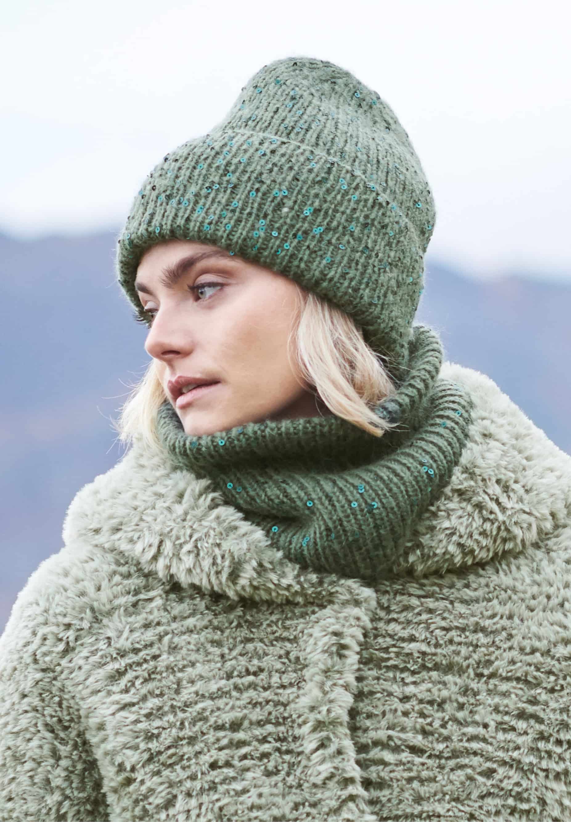 Frau trägt gestrickten Loop in Dunkelgrün mit Pailletten: Modell 20 aus Lovewool No. 23