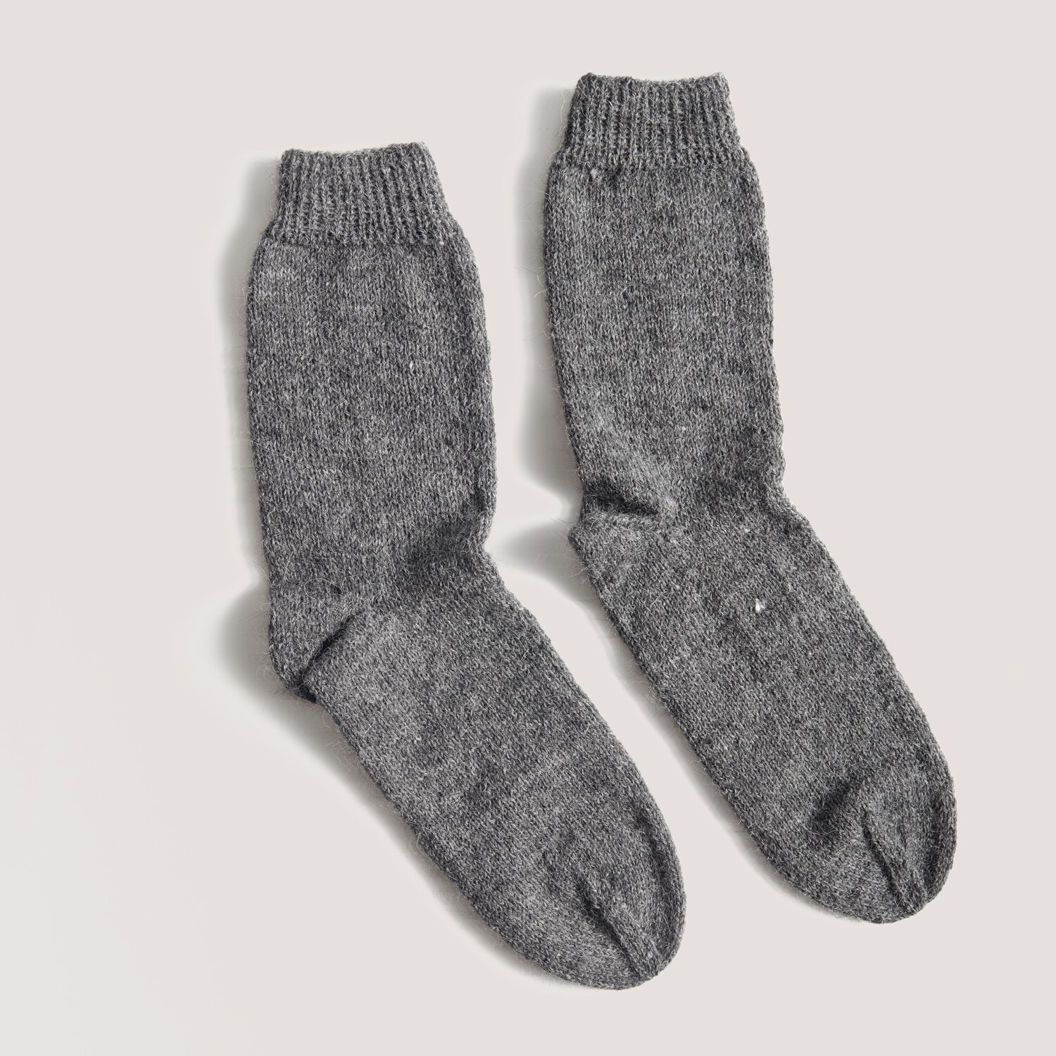 Made by Me Men No. 3 Socken aus grauer Wolle, gestrickt mit feiner Struktur, auf hellem Hintergrund.