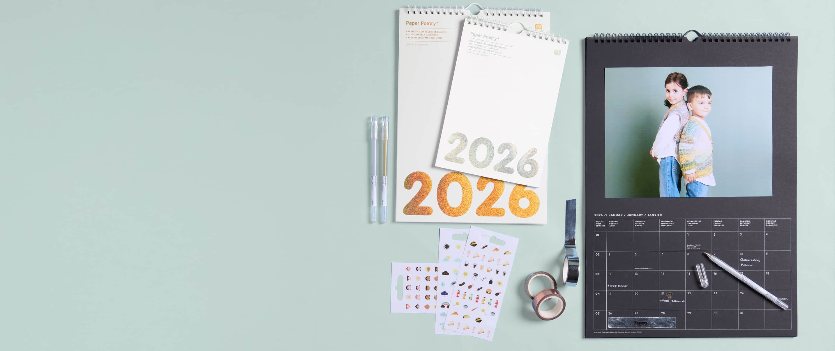 Bastelkalender liegen zum Teil aufgeschlagen auf hellgrünem Hintergrund und sind mit Fotos, Stickern und tapes kreativ gestaltet. 