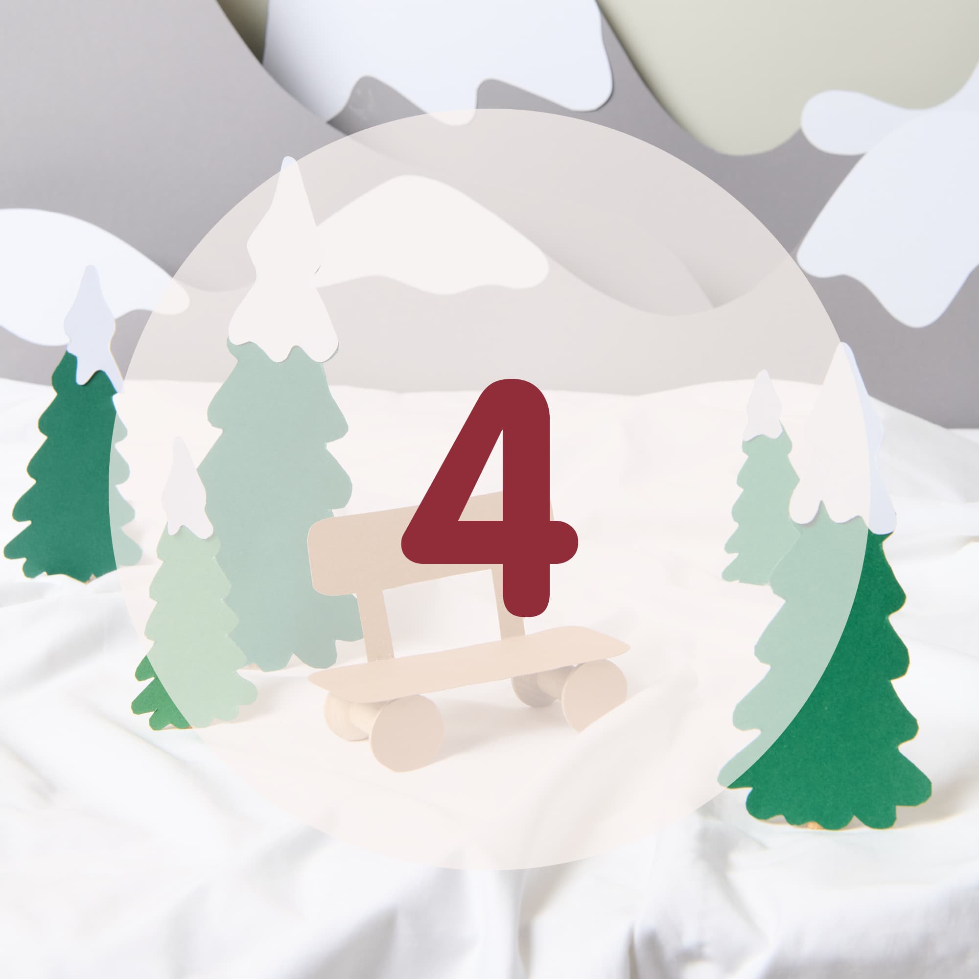 Die Zahl 4 steht in der Mitte vor einer aus Papier gestalteten Schneelandschaft