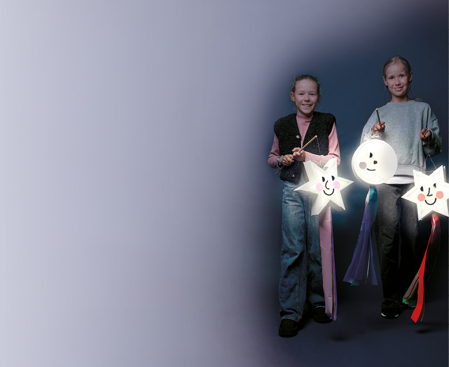 Zwei Kinder halten gebastelte Laternen in Form von Sternen und Mond