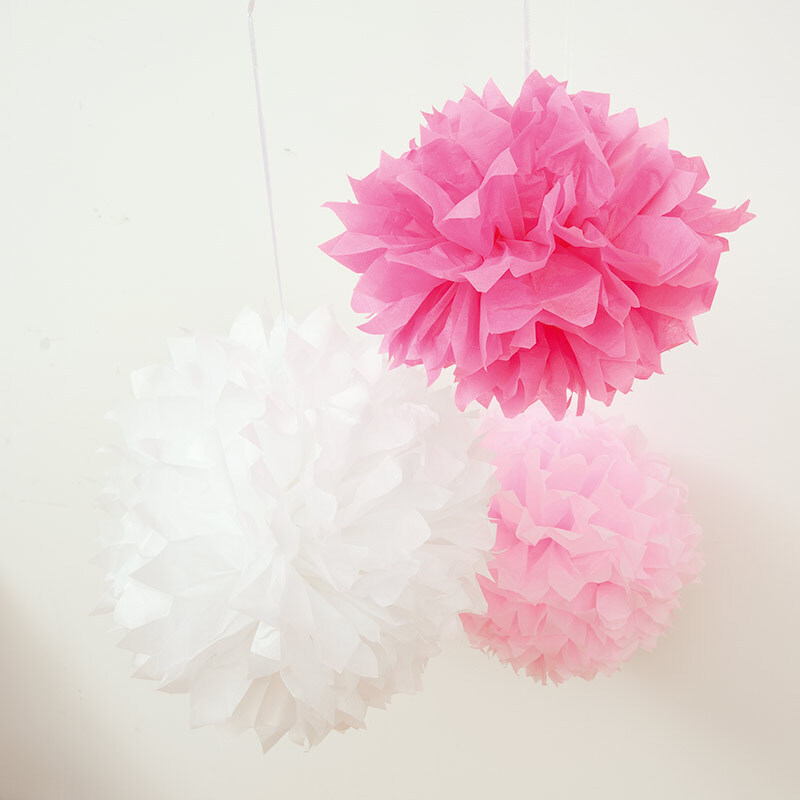 Seidenpapier 50x70cm 5 Bogen von Rico Design: Drei dekorative Pompons in Weiß und Rosa hängen an der Wand.