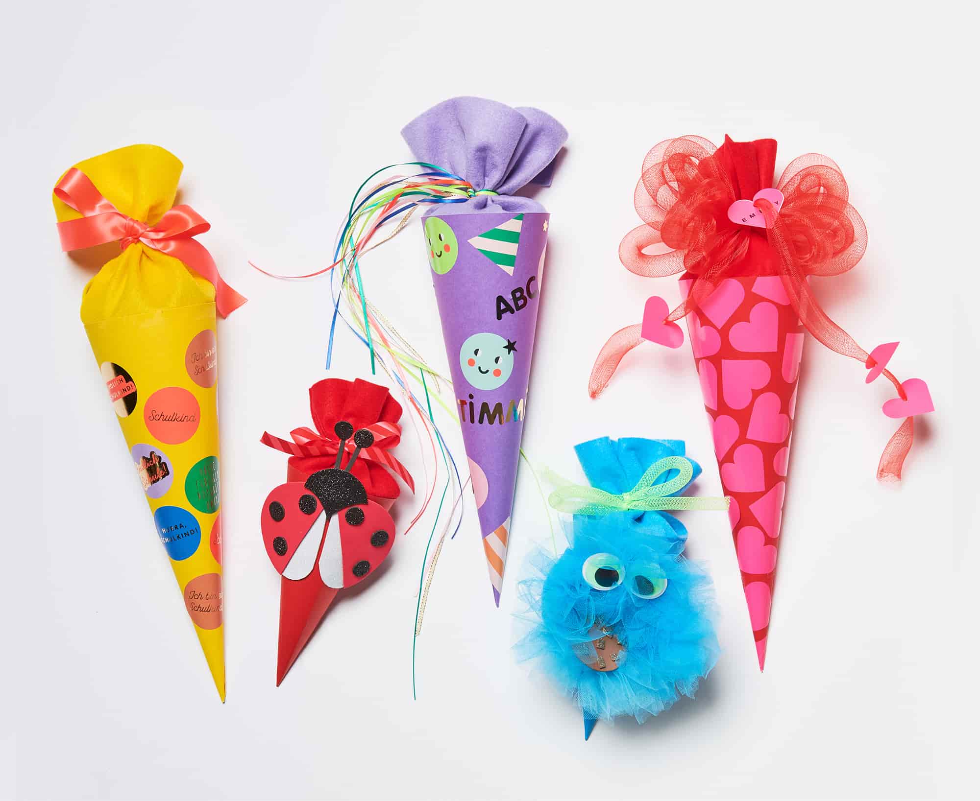 Fünf gebastelte Schultüten in verschiedenen Farben und Designs, darunter Marienkäfer-, Frosch- und Krümelmonsterfigur