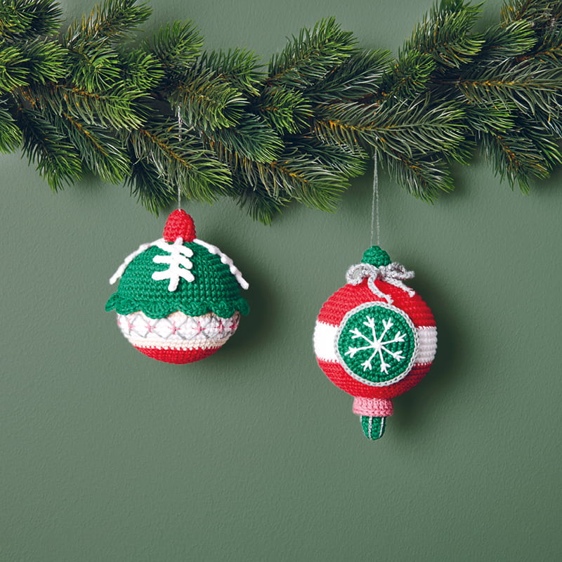 Gehäkelte Weihnachtskugeln hängen an einem Tannenzweig