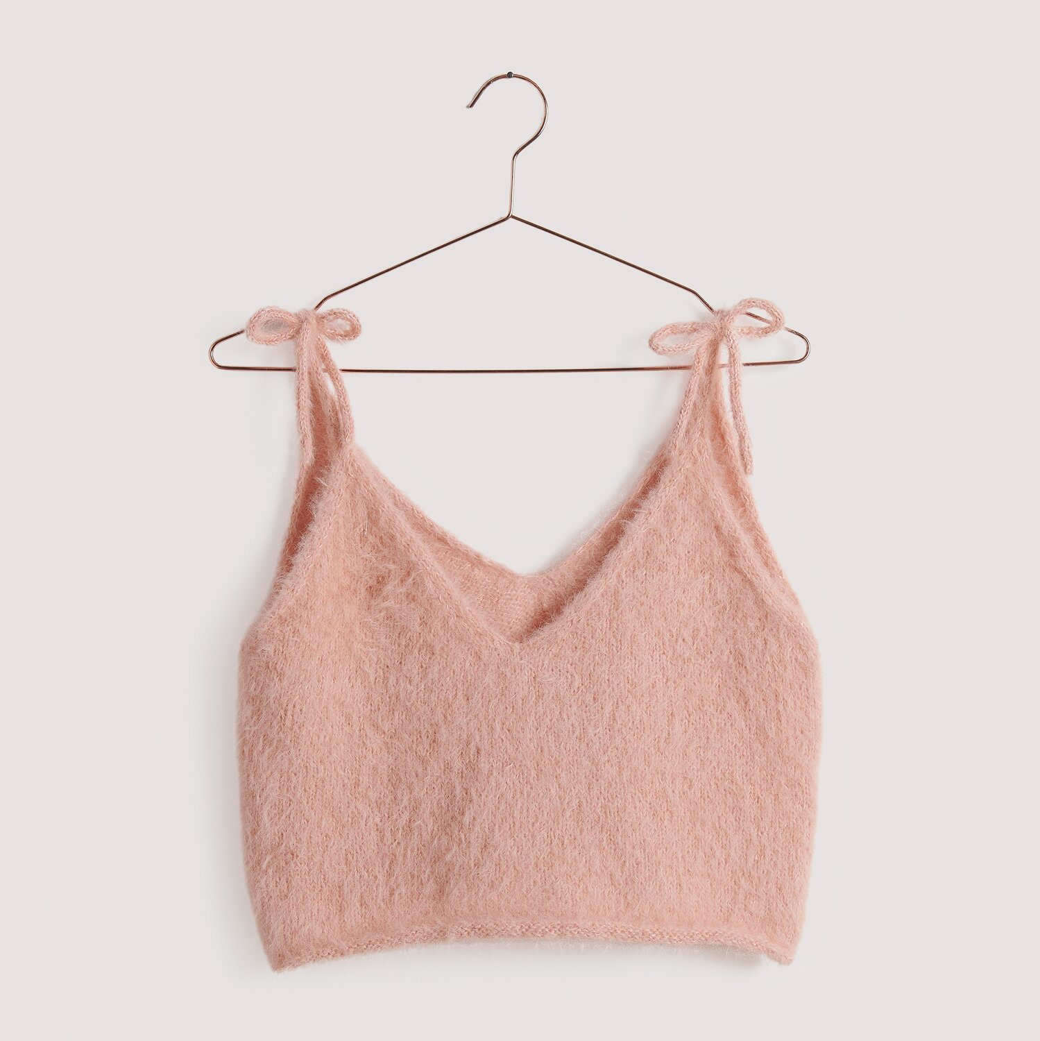 Strickset Top Modell 21, rosa, auf einem Kleiderbügel. Flauschiges Design aus Die Neue Masche No. 15.