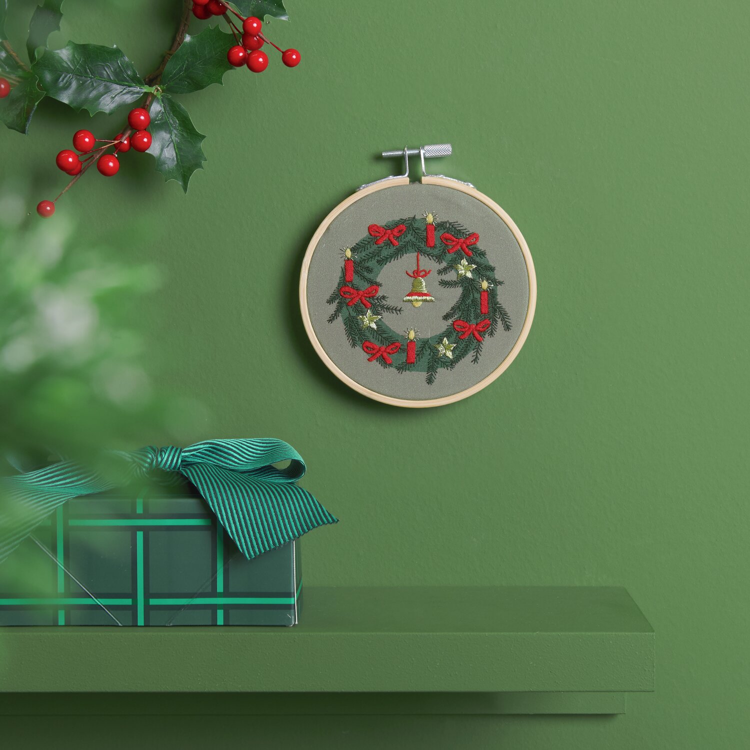 Stickpackung Weihnachtskranz vorgezeichnet Ø10cm von Rico Design Stickpackung Weihnachtskranz vorgezeichnet von Rico Design, zeigt einen festlichen Kranz mit roten Schleifen und Kerzen auf grünem Hintergrund.