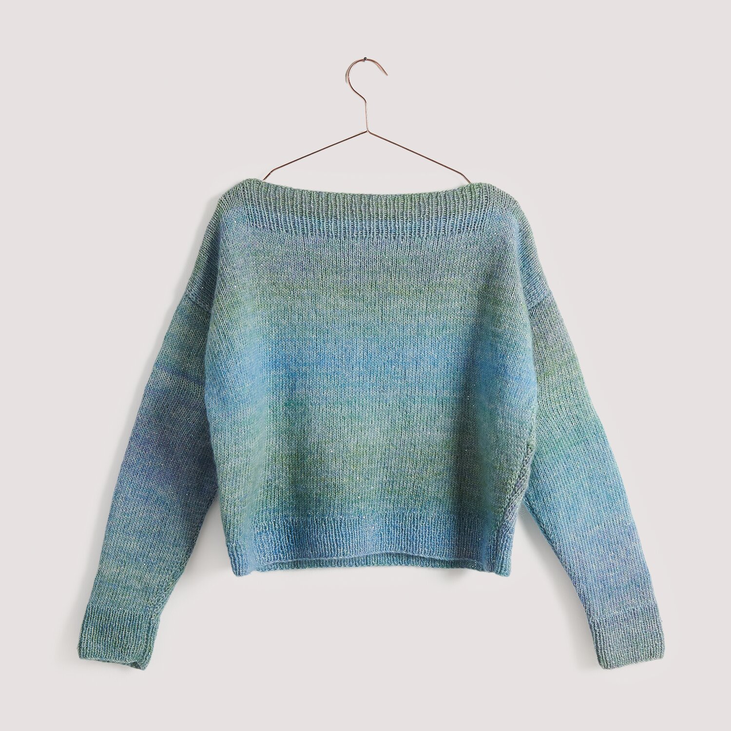 Aqua Shades Pullover in Blau- und Grüntönen auf einem Kleiderbügel vor neutralem Hintergrund.