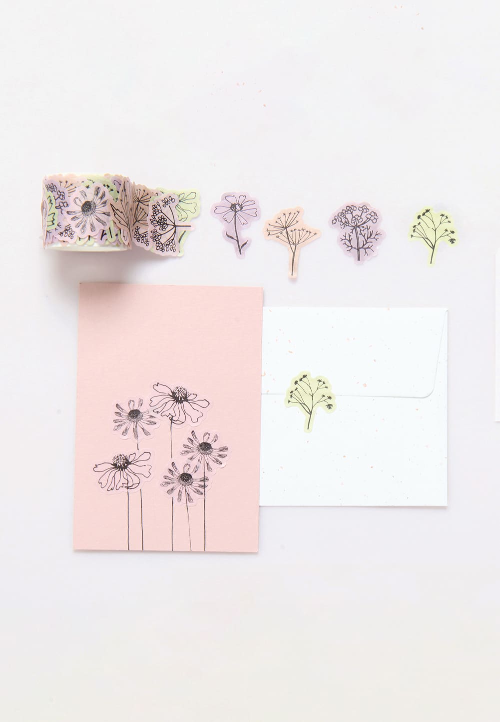 Eine Washisticker-Rolle mit Blumenmotiven und Karten, die mit Stickern dekoriert sind, liegen auf grauem Hintergrund. 