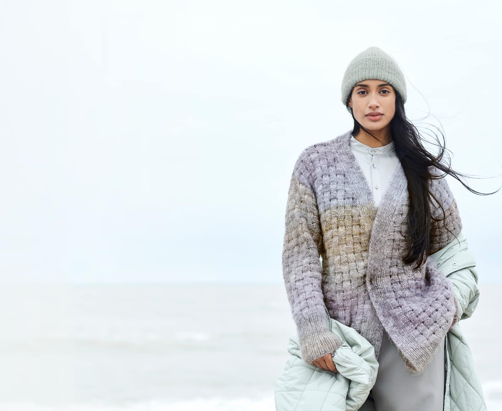 Eine Frau trägt eine gestrickte Jacke und Mütze 