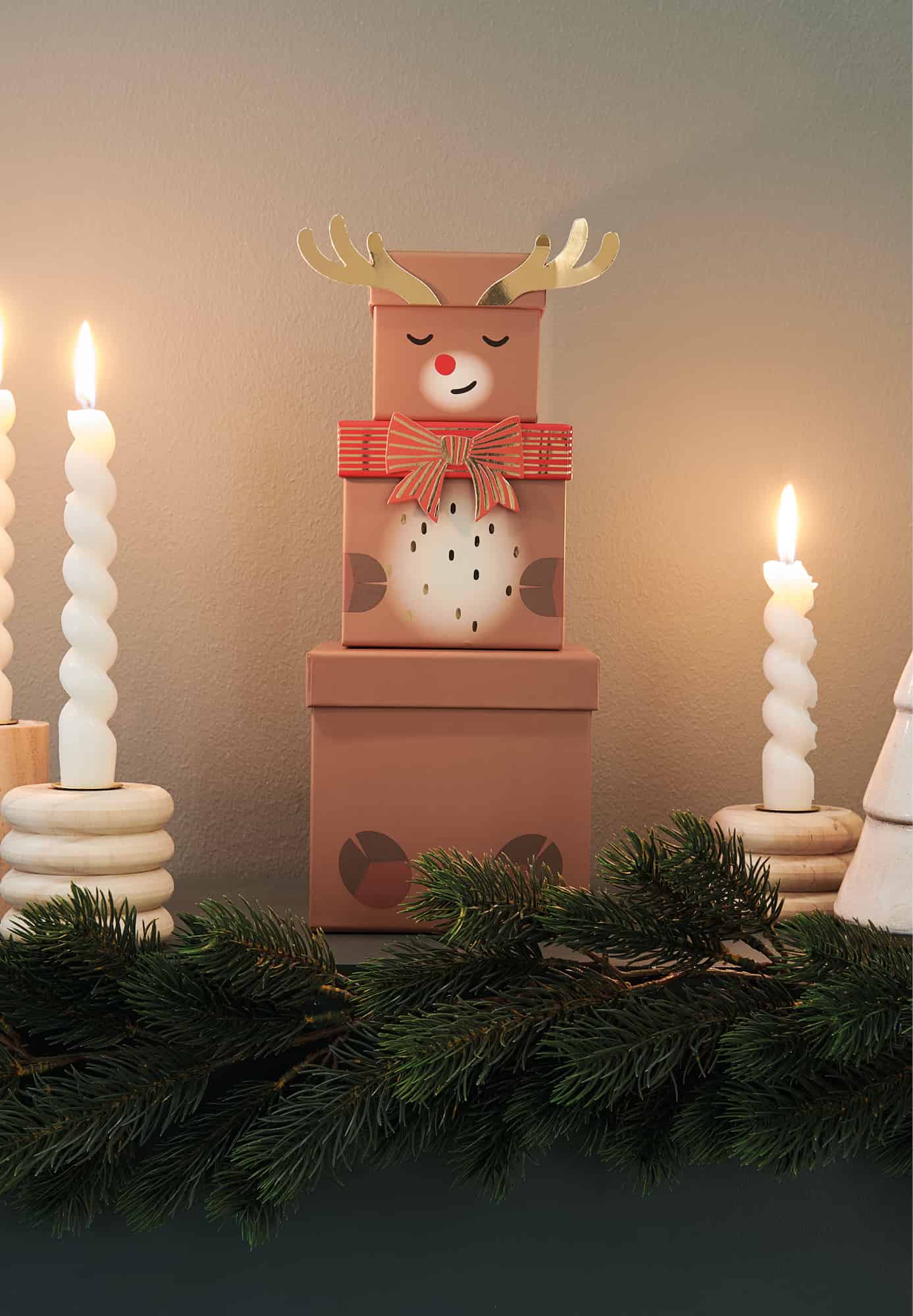 Drei gestapelte Boxen mit Rentier-Motiv stehen in weihnachtlich dekorierter Umgebung