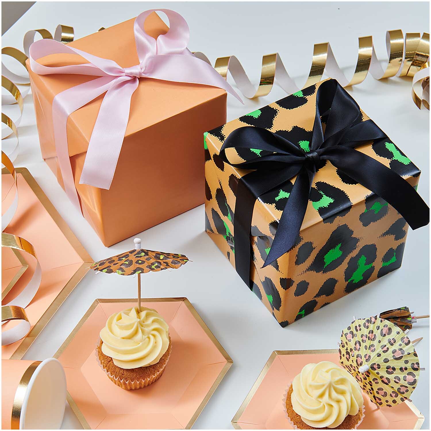 Paper Poetry Geschenkpapier umhüllt stilvoll verpackte Geschenke mit Schleifen, umgeben von Cupcakes und Dekorationen.