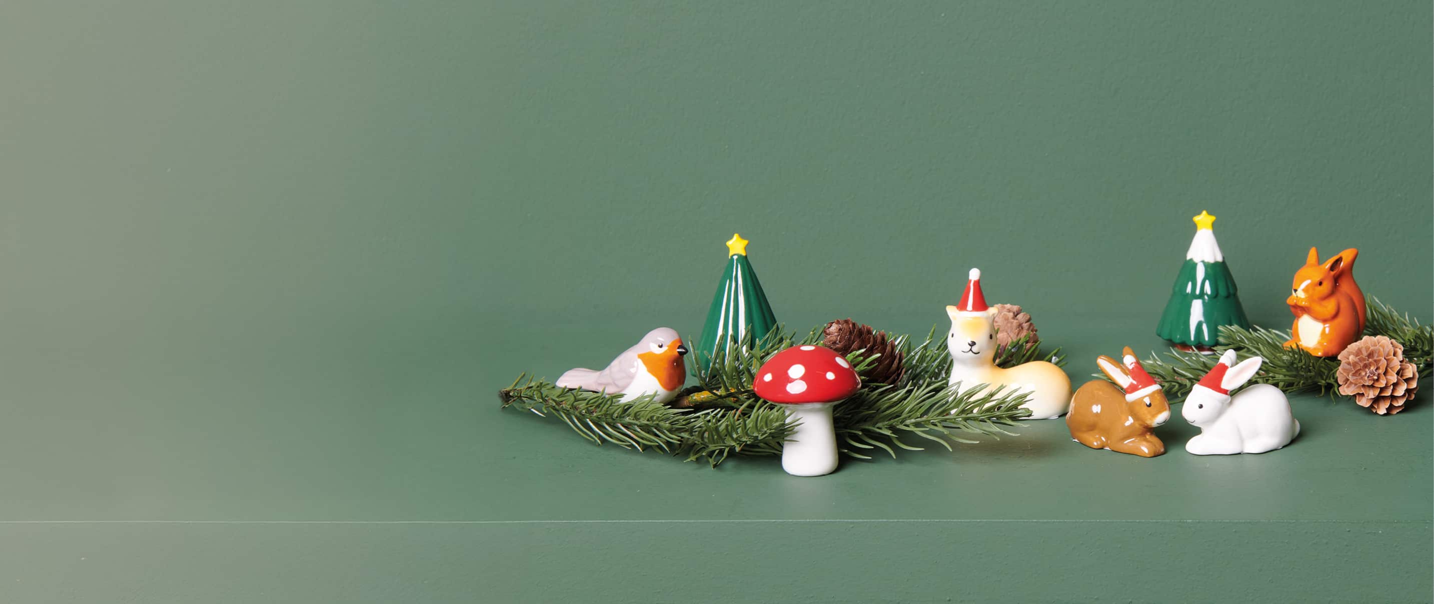 Auf einem grünen Regal sind Weihnachtsfiguren aus Porzellan dekoriert.