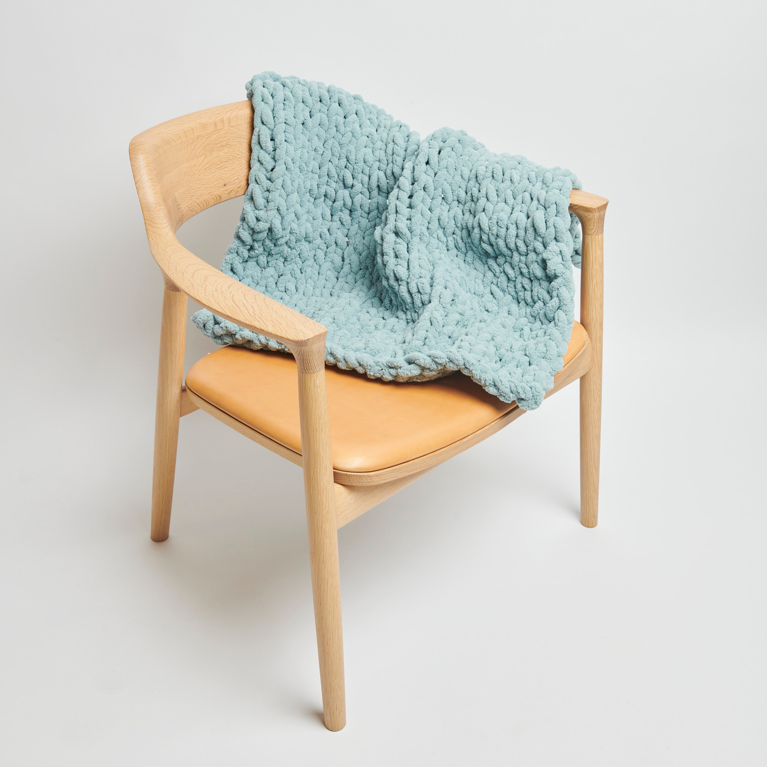 Chenillove Super Big 300g 36m Farbe Aqua von Rico Design Chenillove Super Big: Weiche, aquafarbene Strickdecke von Rico Design auf einem Holzstuhl drapiert.