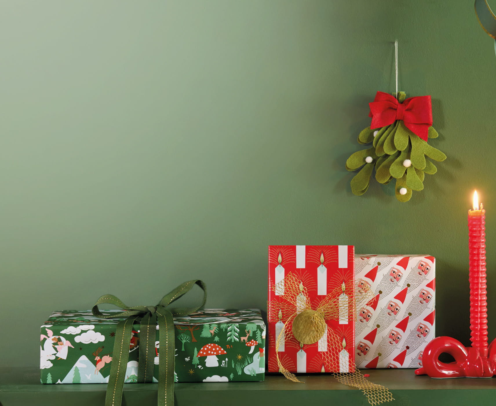 Weihnachtlich verpackte Geschenke mit Geschenkanhängern und Dekoration unter einem Mistelzweig mit roter Schleife.