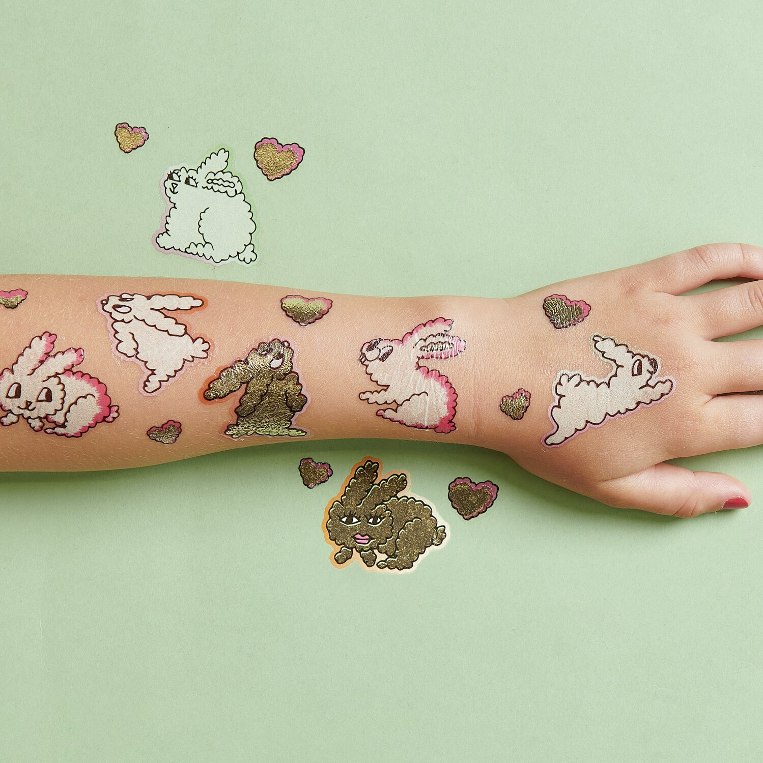 Tattoos Hasen: Temporäre Hasen-Tattoos von Rico Design auf einem Arm, umgeben von bunten Herzen.