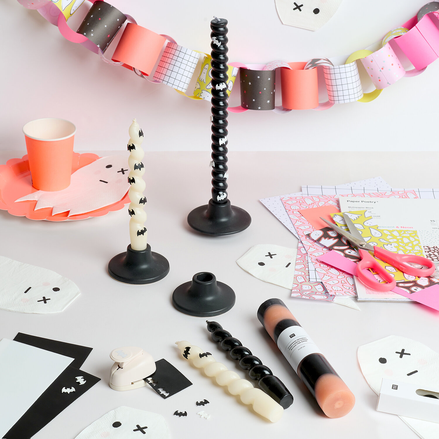 Anleitung Halloween-Kerzen verzieren, Bastelset mit gewundenen Kerzen, Haltern, Papierdeko, Schere und Fledermaus-Stickern auf kreativem Arbeitstisch