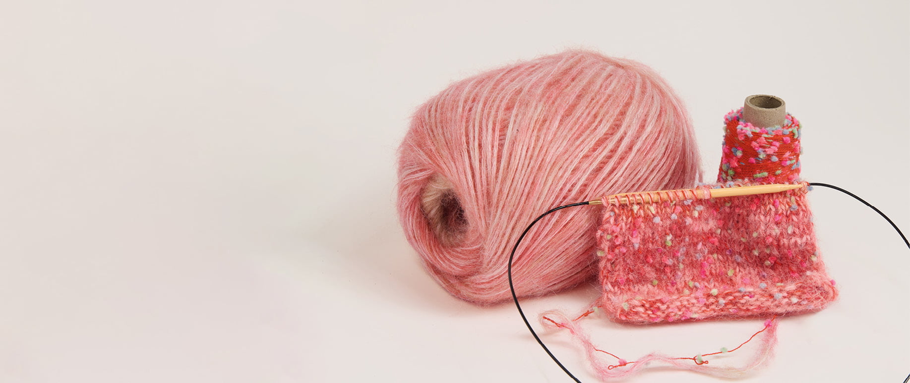 Effektgarn „Creative Make It Flöckchen“ als Garnknäuel mit angestrickter Maschenprobe auf hellem Hintergrund.