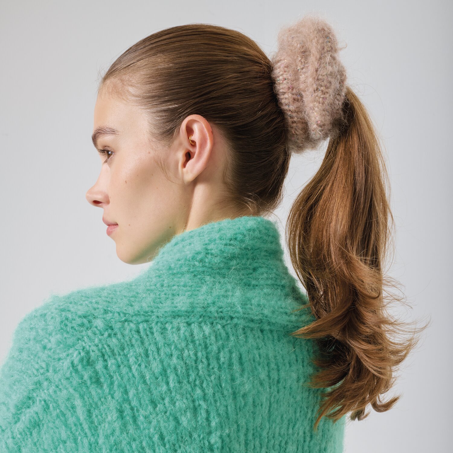 Strickset Scrunchie Modell 18a aus Made by Me No. 21 von Rico Design Strickset Scrunchie Modell 18a: Frau mit beigem Scrunchie im Haar, trägt mintgrünen Pullover.
