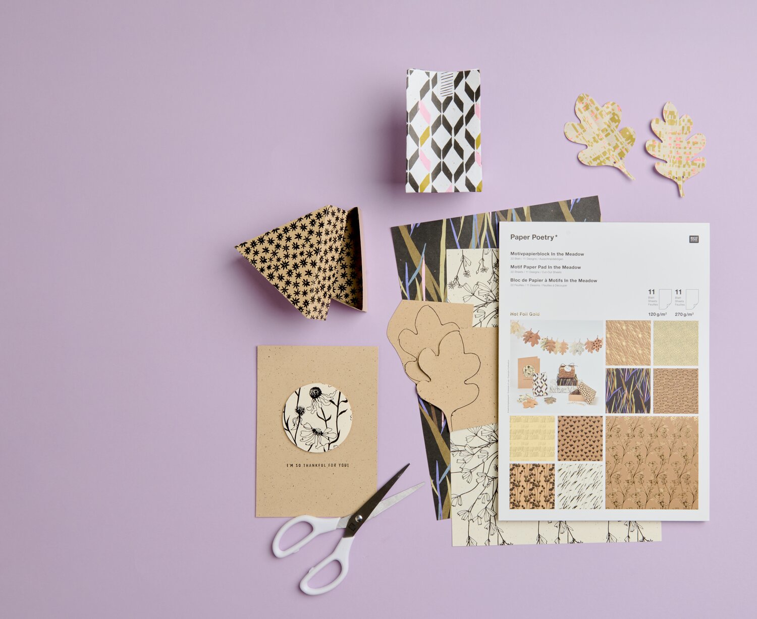 Paper Poetry Motivpapierblock In the Meadow 21 Blatt, Rico Design, A4, kreative Bastelszene mit zugeschnittenem Motivpapier, Schere, Boxen und Blattformen auf lila Untergrund