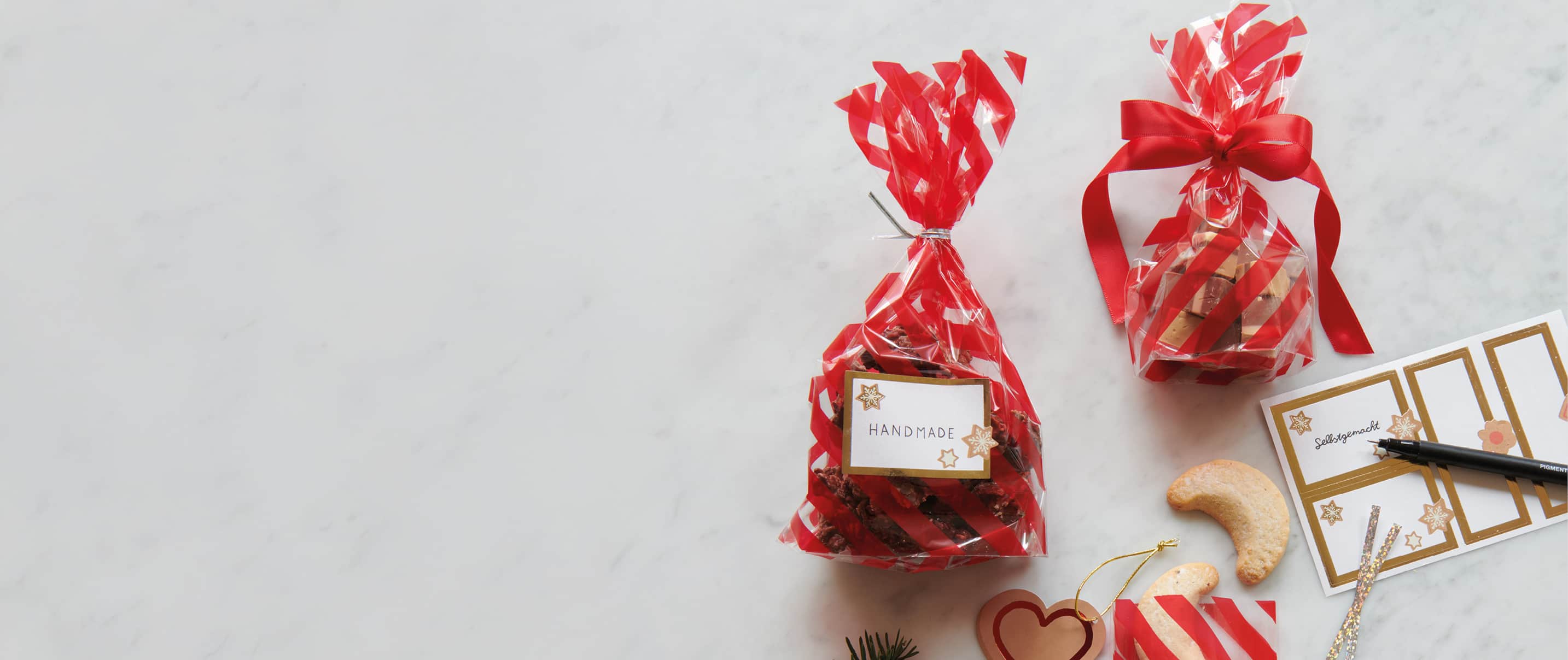 Gefüllte Tüten mit Keksen liegen mit Etiketten-Stickern auf einem Marmor-Untergrund.