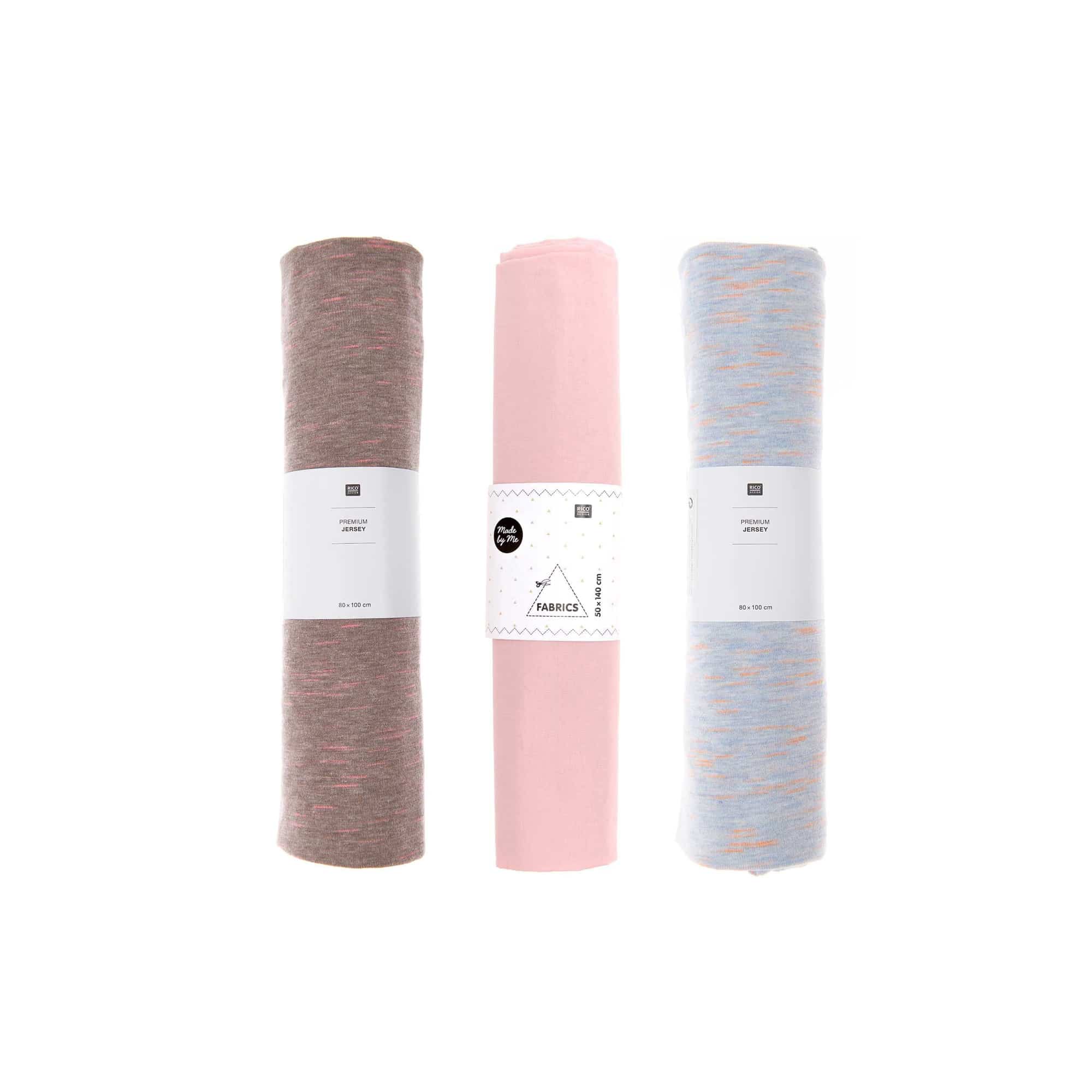 Drei Stoffrollen in den Farben braun, rosa und blau liegen nebeneinander
