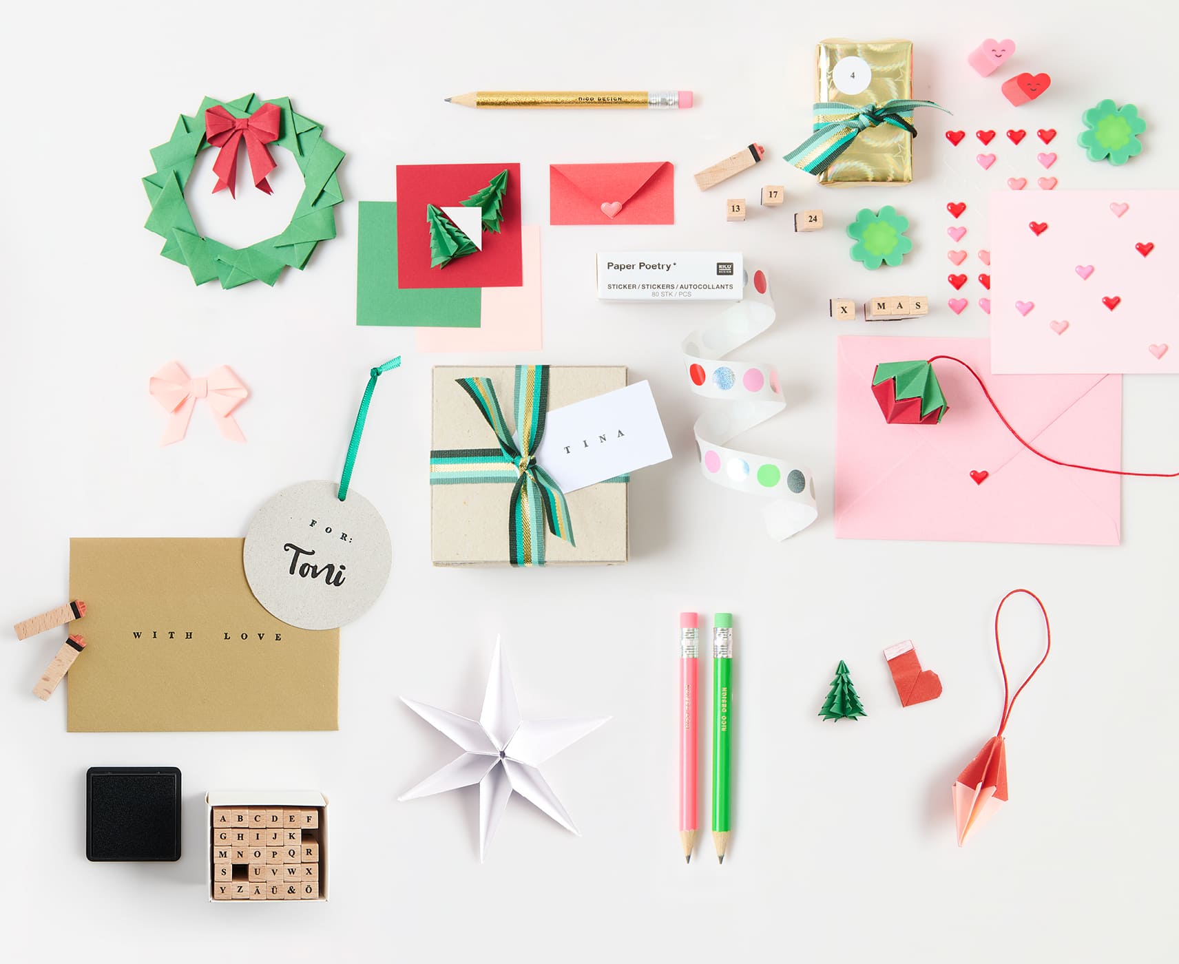 Papeterie-Artikel wie Origami-Papier, Stempel, und Sticker im Mini-Format liegen ausgebreitet auf weißem Hintergrund 