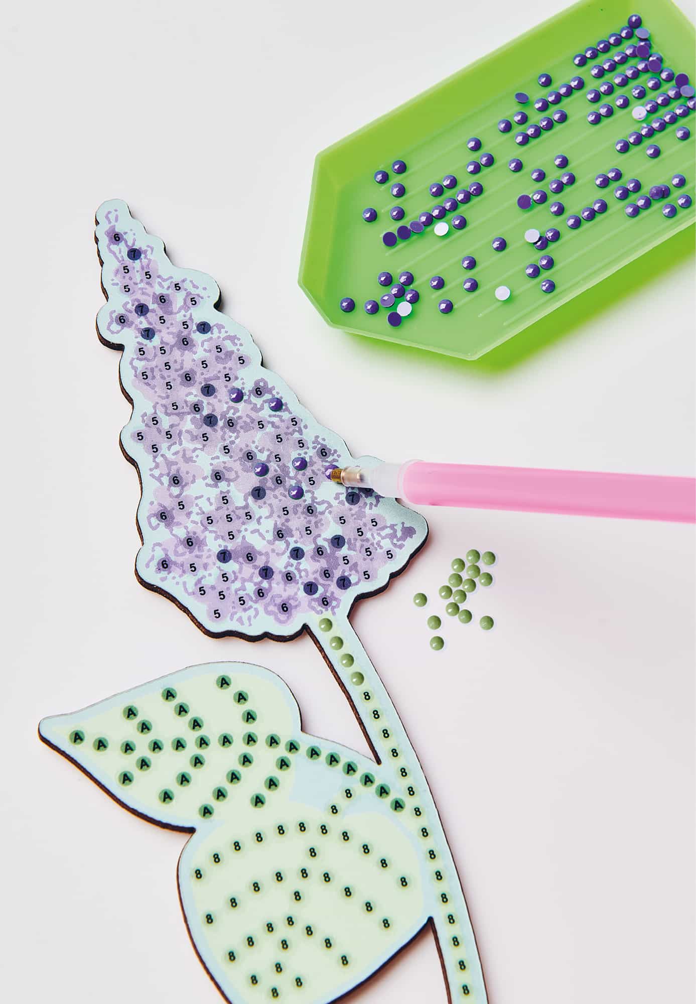 Eine Blume aus einem Diamond Painting Set wird mit Strasssteinen beklebt.