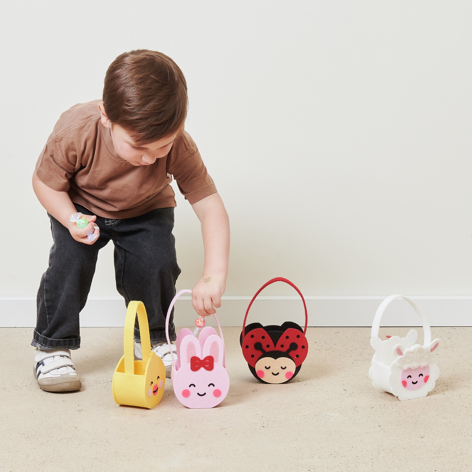 Filz-Korb Marienkäfer, Hase, Küken und Lämmchen von Rico Design. Kind spielt mit bunten Körben.