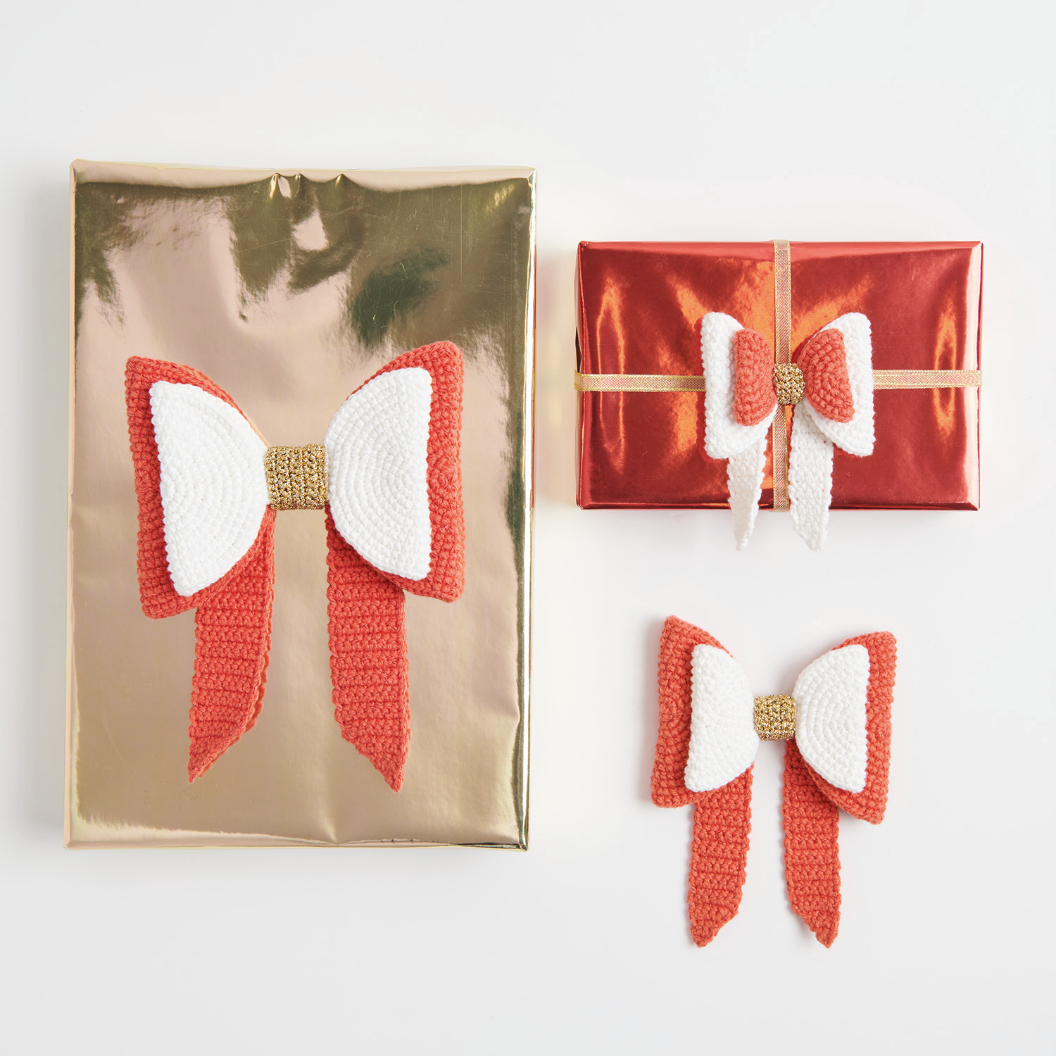 Häkelanleitung Ricorumi Manga Schleife: Drei Geschenke mit roten und weißen Schleifen auf gold- und rotfarbenem Papier.