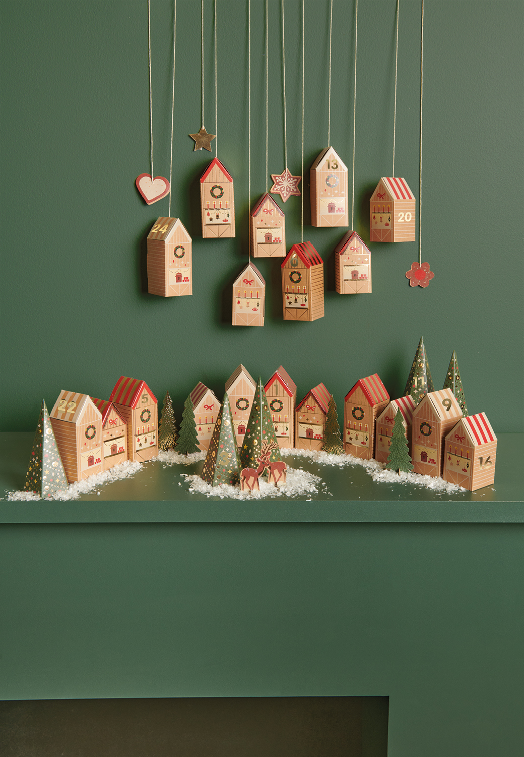 Adventskalendertürchen mit Papphaus- und Tannenoptik sind dekorativ auf einem Kaminsims aufgestellt und aufgehängt