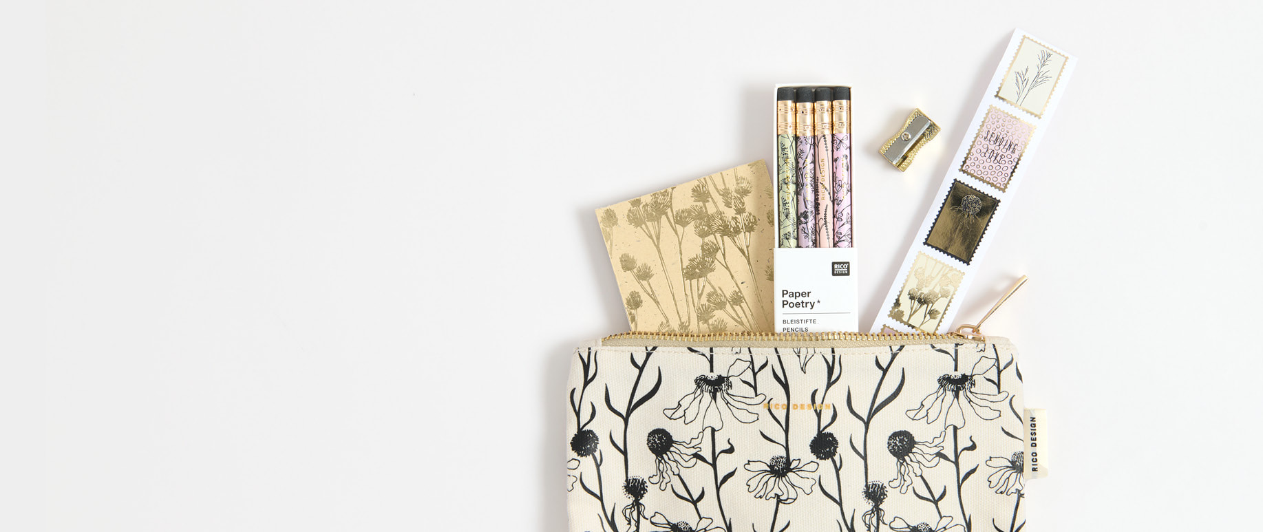 Ein Etui mit schwarzem Blumenmuster ist gefüllt mit Notizblock, Stiften und Stickern. 