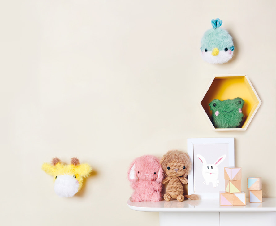 Gehäkelte Tiere mit flauschigem Fell sind an einer Wand und auf einem Regal dekoriert.
