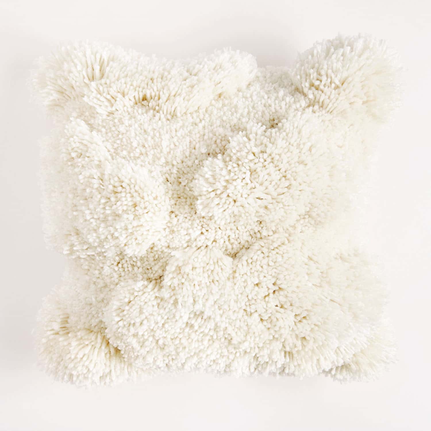 Geknüpftes, cremefarbiges Kissen mit unterschiedlich langen Knüpffäden