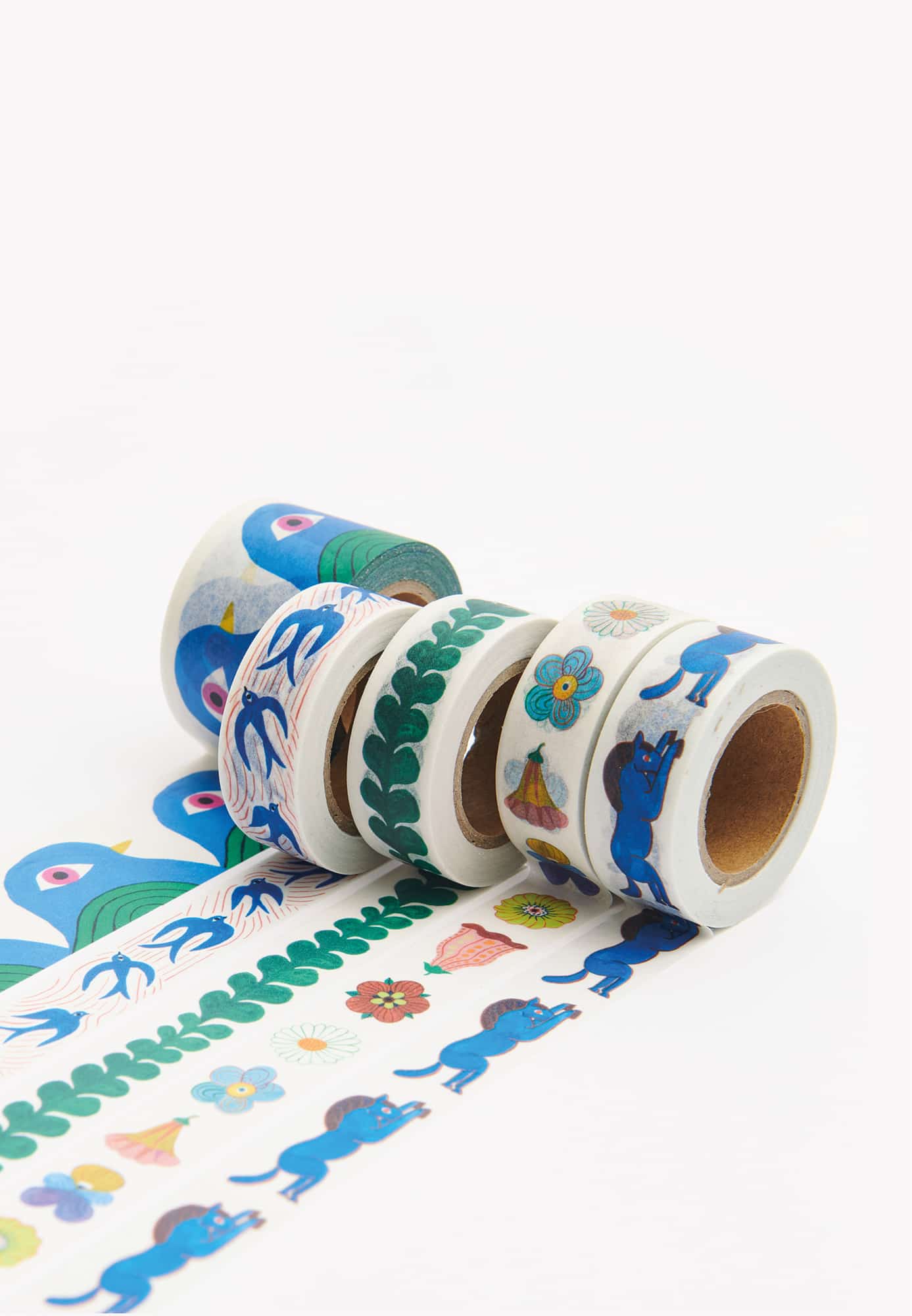 Washi Tape Rollen mit Illustrationen von Vögeln, Blumen und Pferden liegen ausgerollt auf hellem Untergrund