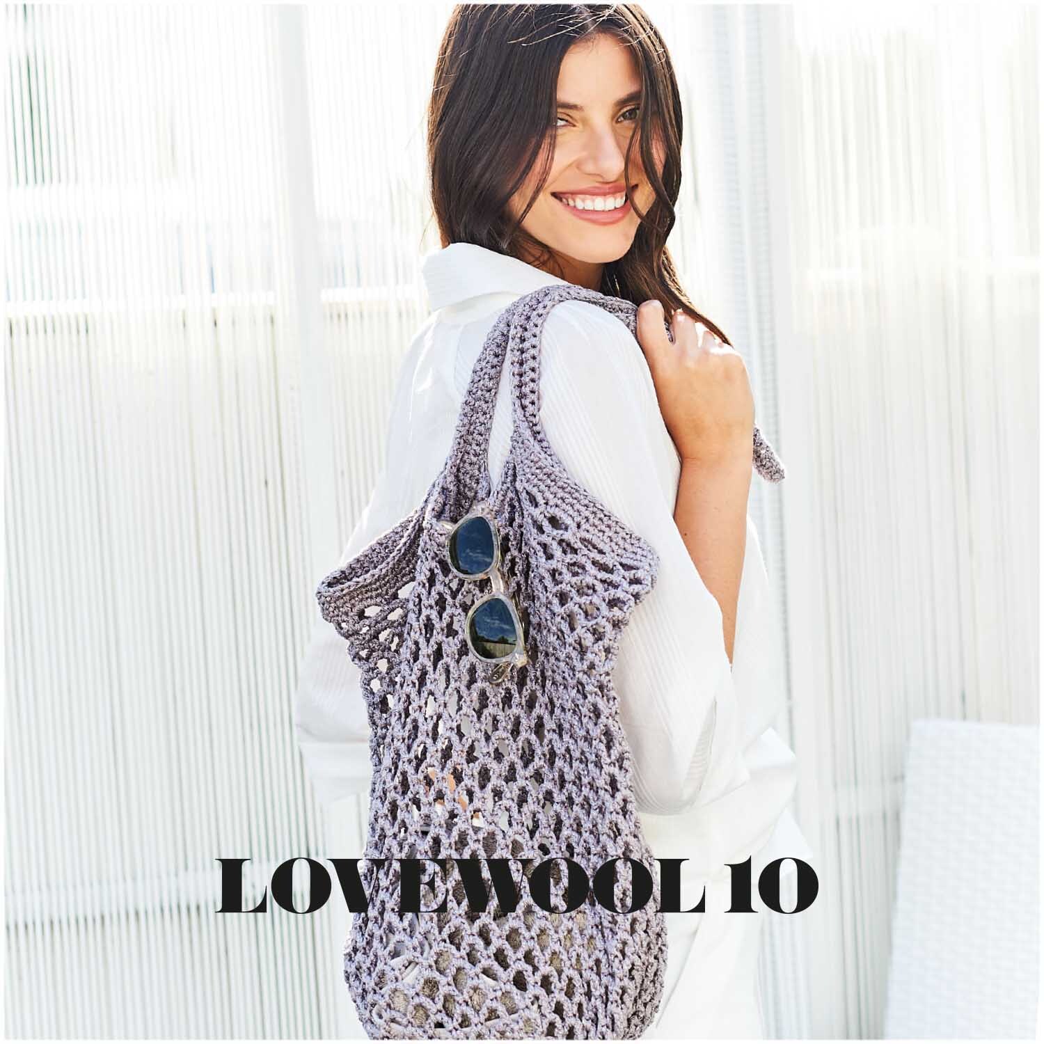 Fashion Cotton Métallisé dk 50g 125m Farbe Eisen von Rico Design Fashion Cotton Métallisé dk: Frau mit gehäkelter Tasche aus Eisen-grauem Garn, lächelnd in weißem Outfit.